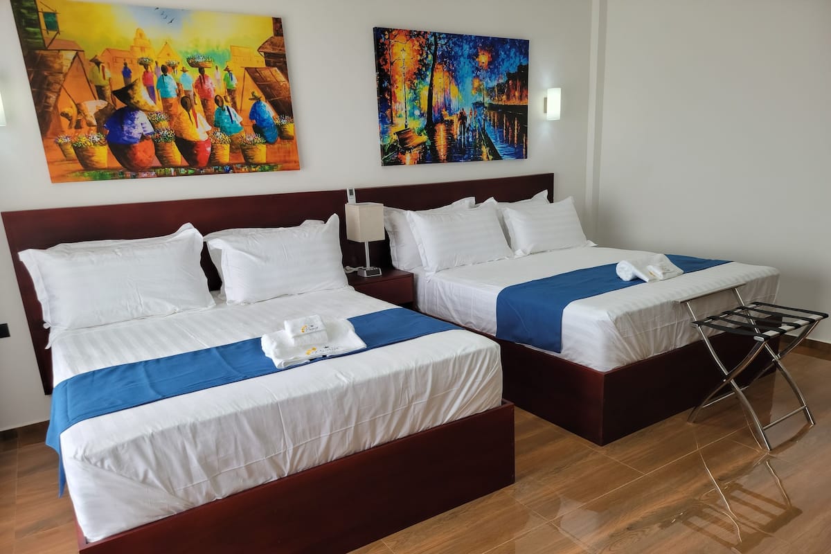 Ein Hotelzimmer mit zwei Betten, Holzboden und zwei Bildern an der Wand.