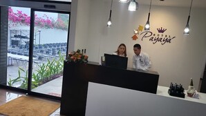 A hotel reception desk with a large window overlooking a seating area and a garden.
