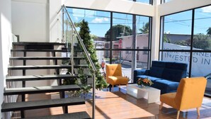 A modern interior with a staircase, a blue sofa, and a yellow armchair.