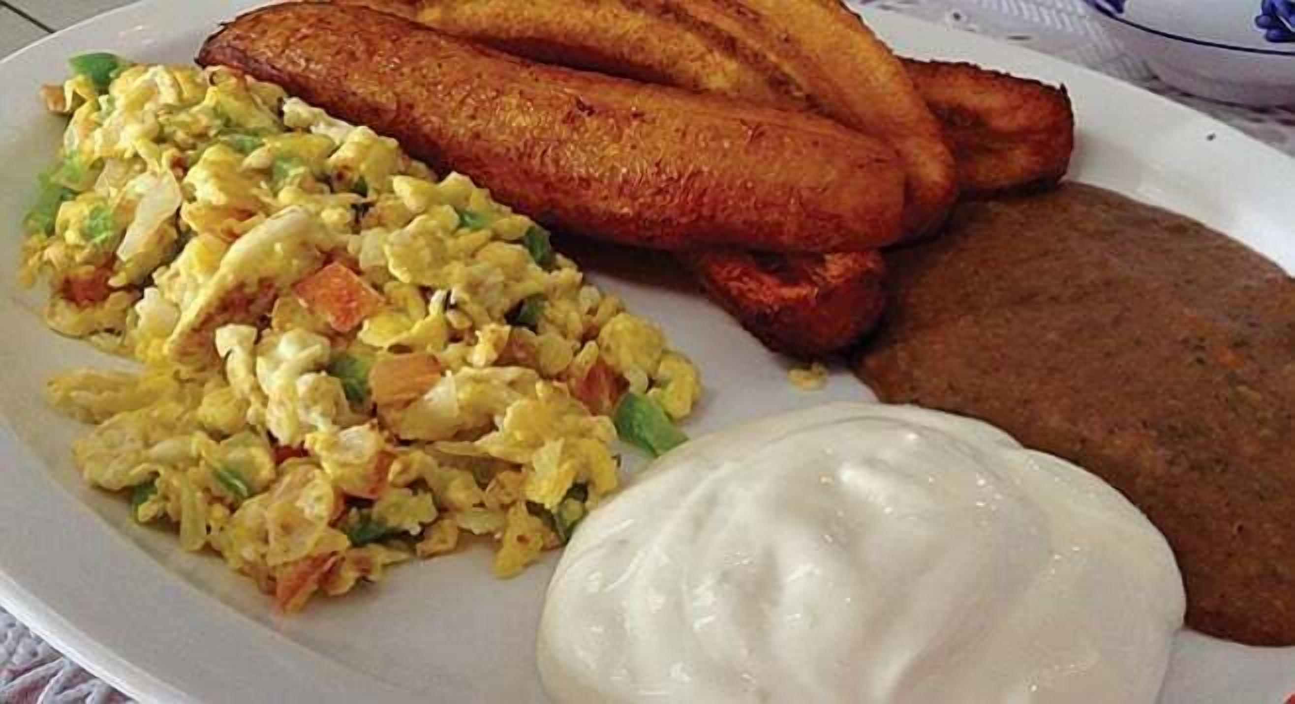 A plate with fried plantains, scrambled eggs with vegetables, and a piece of fried bread.