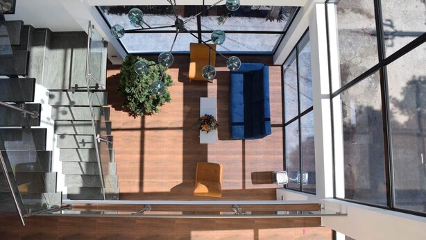 A modern interior with a staircase, a blue sofa, and a potted plant.