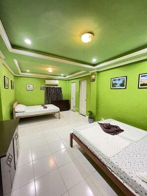 A room with two beds, a desk, and a potted plant. - Bahay Ni Ate Bed and Breakfast (Puerto Princesa)