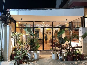 A coffee shop entrance with a 'Welcome' sign, potted plants, and a glass door. - Bahay Ni Ate Bed and Breakfast (Puerto Princesa)