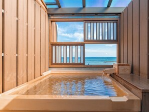 Un bain à remous en bois avec vue sur l’océan.
