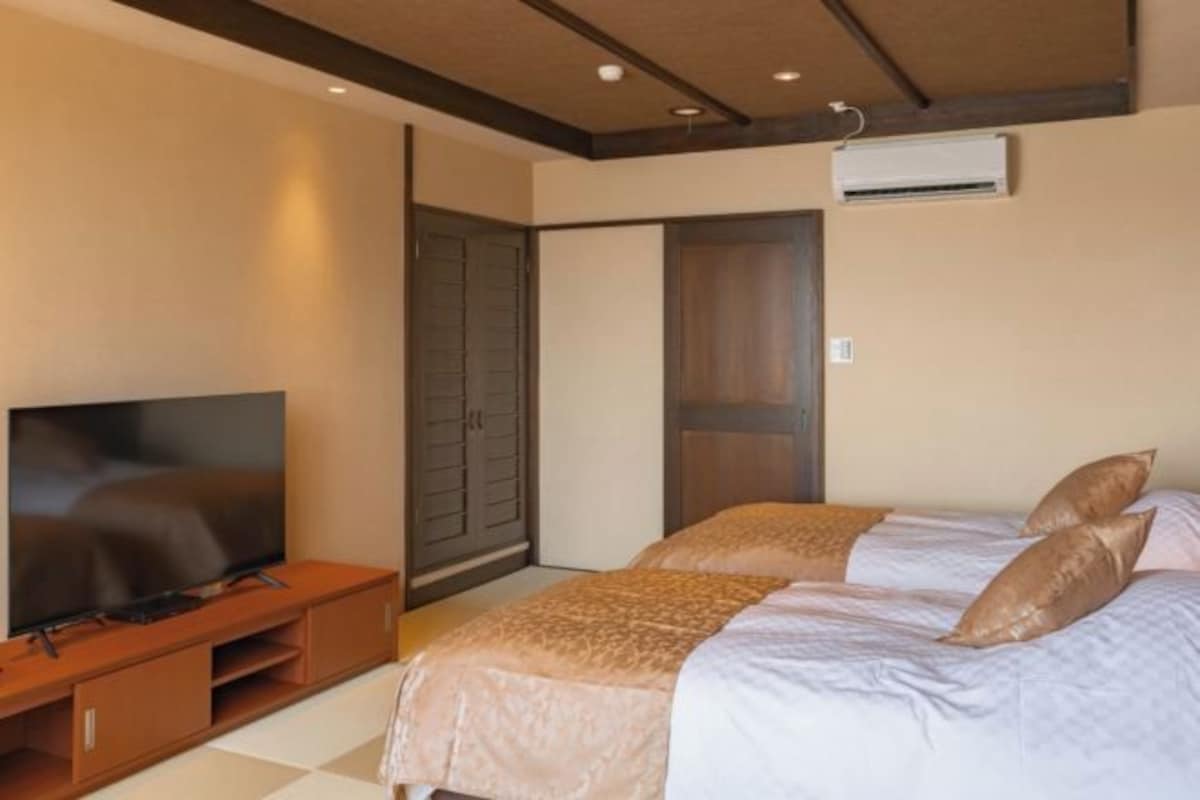 Una habitación de hotel con una cama, un televisor sobre un soporte de madera y un armario.