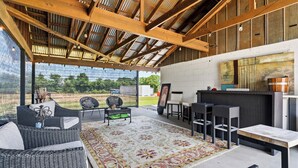 An open-plan living area with a high ceiling, outdoor view, wicker furniture, and a patterned rug. - Spa Weekend Near WinStar Spa or Golf Included (Thackerville)