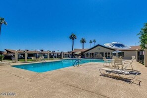 Relax by the rectangular pool surrounded by a tiled deck and lounge chairs, with umbrellas for shade.