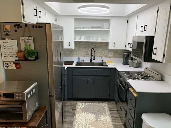 Prepare meals in the kitchen with an oven and stainless steel range hood, featuring a large island with a sink and ample counter space.