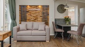 Un salon comprenant un canapé, une table à manger, des chaises, une horloge et un mur décoratif.