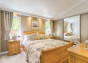 Un dormitorio con cama de madera, mesitas de noche, un espejo y una ventana con cortinas.