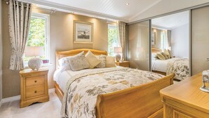 Ein Schlafzimmer mit einem hölzernen Bett, Nachttischen, einem Spiegel und einem Fenster mit Vorhängen.