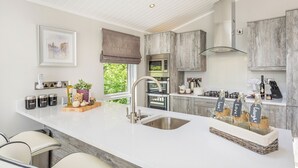 Eine moderne Küche mit weißer Arbeitsplatte, Spüle aus Edelstahl und Barhocker.