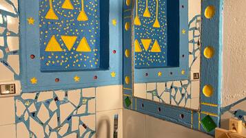 A bathroom with a mosaic tile wall, a large sink, and decorative elements like bells and stars.