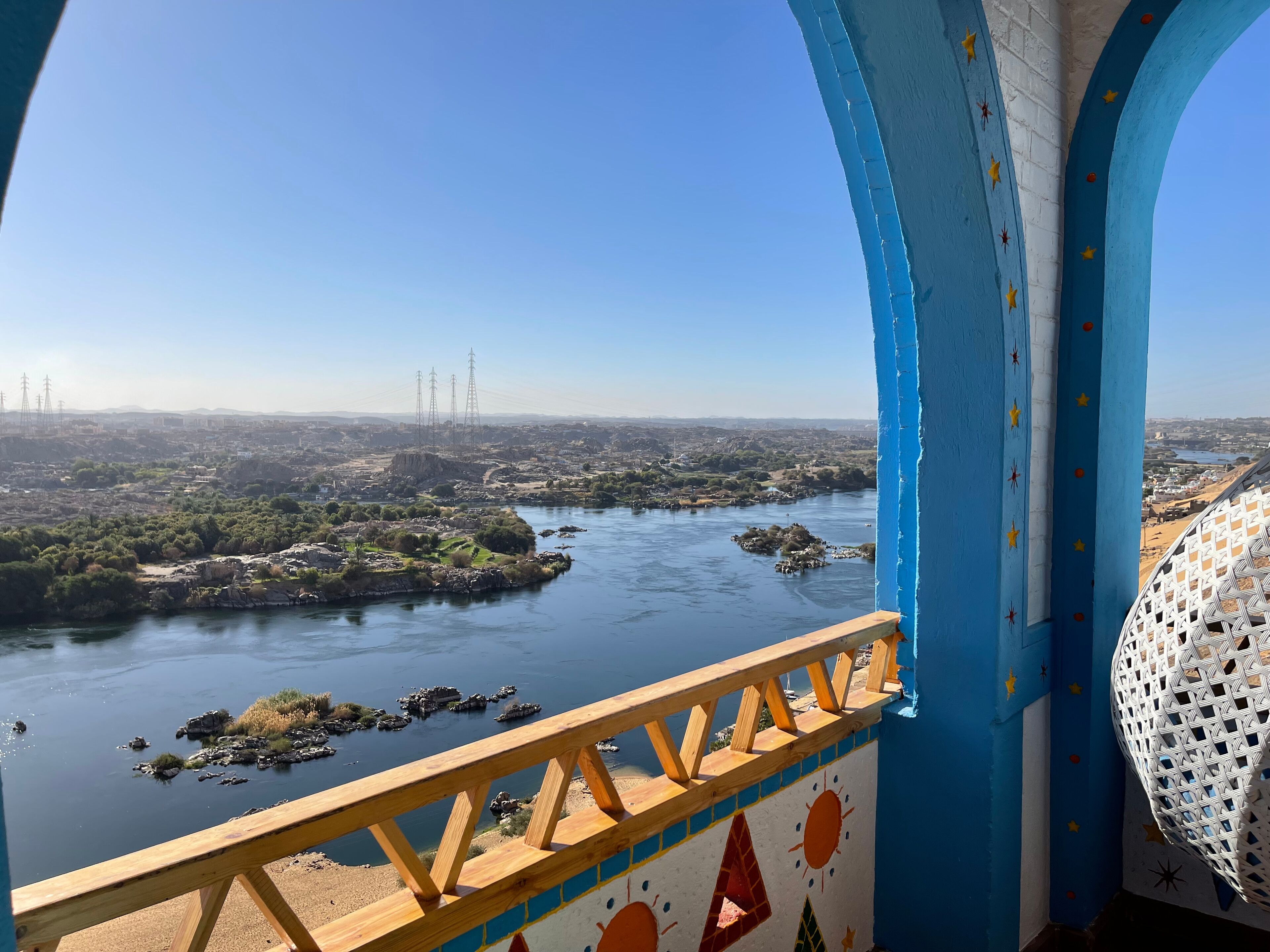 Une vue depuis un balcon doté d’une balustrade, donnant sur une rivière parsemée d’îles et sur une ville lointaine.
