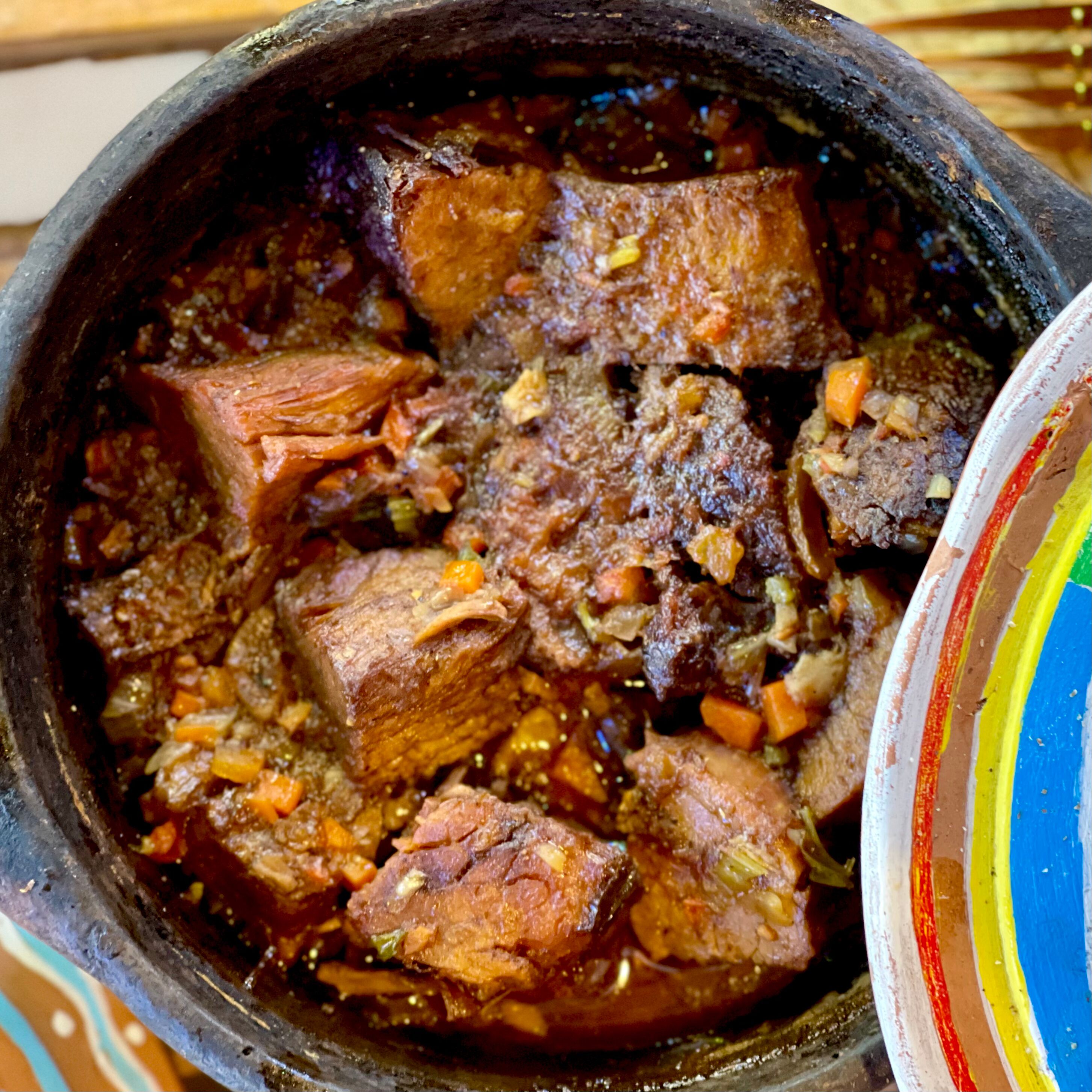 A traditional clay pot filled with a stew containing chunks of meat and vegetables.