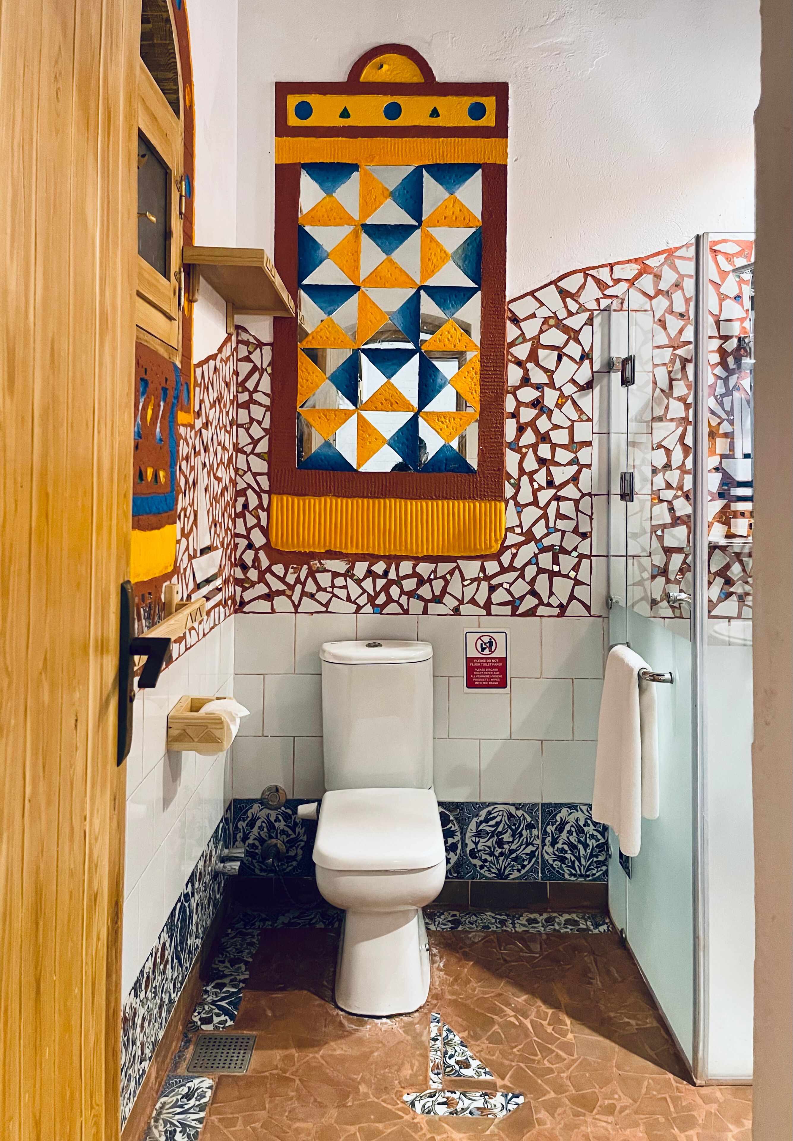 Un baño con inodoro, ducha y pared de mosaicos.