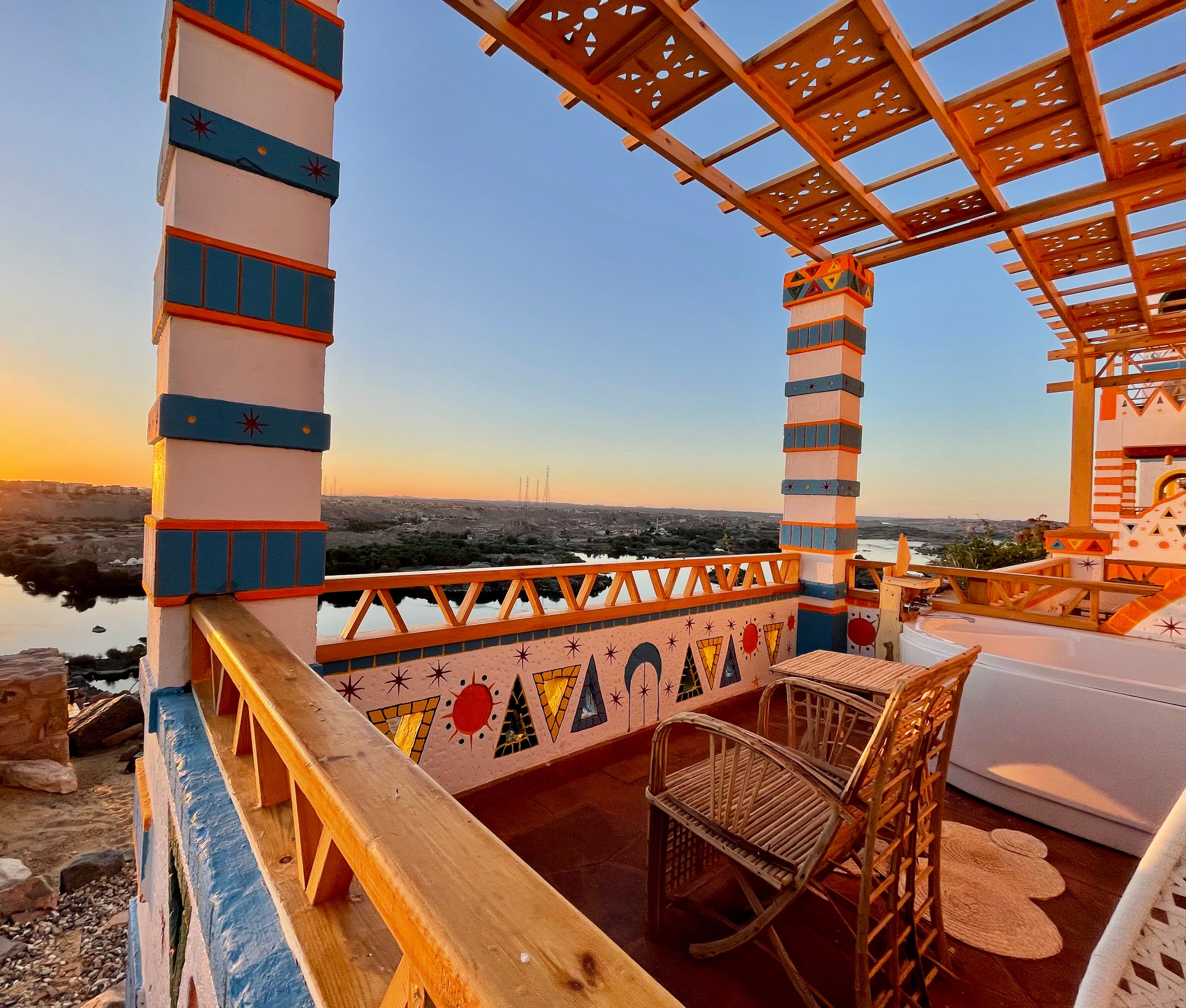 Une terrasse offrant une vue sur un paysage lointain, agrémentée d’une balustrade en bois et d’une seule chaise en osier.