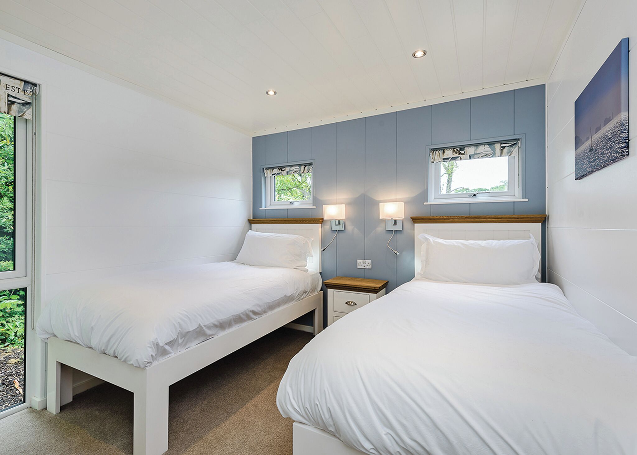 A bedroom with two beds, a window, and a nightstand.