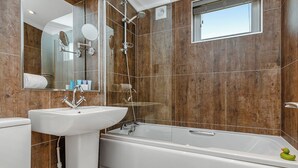 A modern bathroom with a bathtub, a sink, and a shower. - 3 bedroom accommodation in Cheddar (Cheddar)