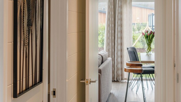 An open door leading to a balcony with a view of a garden, a table with chairs, and a vase with flowers. - 3 bedroom accommodation in Cheddar (Cheddar)