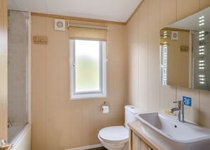 Une salle de bain équipée de toilettes, d’un lavabo, d’un miroir et d’une fenêtre.