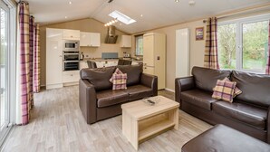 A modern living room with a sofa set, a coffee table, and a kitchen in the background. - 1 bedroom accommodation in Bewaldeth, Keswick (Bewaldeth, Keswick)