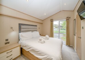 Ein Hotelzimmer mit Bett, Fernseher, Fenster und Tür.