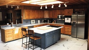 A kitchen with wooden cabinets, a central island, a stainless steel refrigerator, and a skylight. - 4B Lakefront home off M22 with access to Lake Michigan! (Onekama)