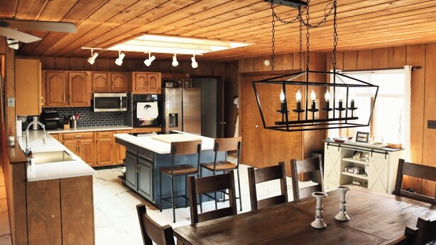 A kitchen with wooden cabinets, a central island, and a hanging light fixture. - 4B Lakefront home off M22 with access to Lake Michigan! (Onekama)