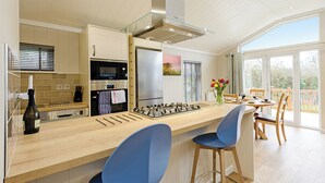 A modern kitchen with a central island, bar stools, and a dining area with a view.
