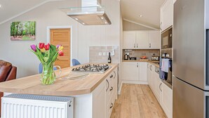 A modern kitchen with a central island, white cabinetry, a stainless steel refrigerator, and a gas stove.