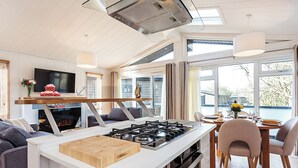 A modern kitchen with a central island, a dining area with chairs, and a TV mounted on the wall. - 2 bedroom accommodation in Wootton Bridge, Nr Cowes (Wootton Bridge, Nr Cowes)