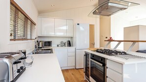 A modern kitchen with white cabinetry, a built-in microwave, a gas stove, and a stainless steel toaster. - 2 bedroom accommodation in Wootton Bridge, Nr Cowes (Wootton Bridge, Nr Cowes)
