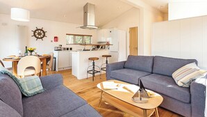 A modern living room with a sofa, a coffee table, and a kitchen area in the background. - 2 bedroom accommodation in Wootton Bridge, Nr Cowes (Wootton Bridge, Nr Cowes)