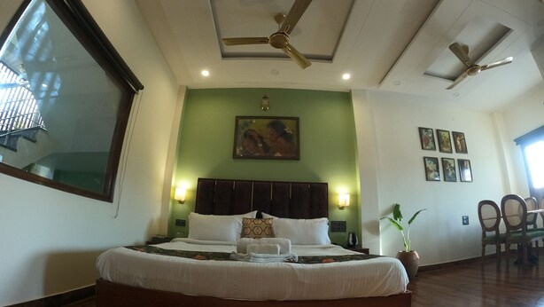 A spacious bedroom with a large bed, ceiling fans, and a green accent wall. - Hotel Sethi Legacy (Haridwar)