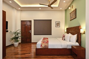 Un dormitorio con una cama de madera, un ventilador de techo, una planta en maceta y un ventanal grande.