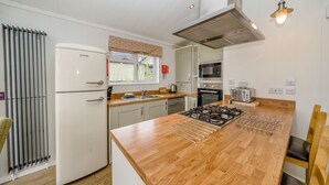 A modern kitchen with a central island, stainless steel appliances, and a window with a view. - Wordsworth Premier Select (Bewaldeth, Keswick)