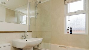 Un baño con lavamanos, espejo, ducha y ventana.