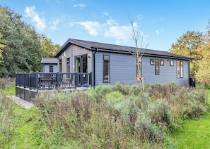 A modern two-story house with a balcony, surrounded by natural vegetation. - Bakewell Premier Lodge (Ashbourne)