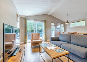 A modern living room with a sofa, armchair, and a glass coffee table. - Bakewell Premier Lodge (Ashbourne)
