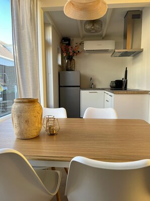 Uma cozinha moderna com armários brancos, geladeira de aço inoxidável e luminária pendente.
