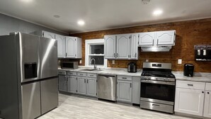 A modern kitchen with stainless steel appliances, white cabinetry, and a wooden accent wall.