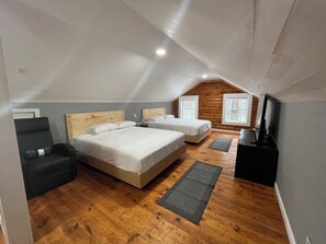 Una camera da letto con un letto grande, un divanetto, una TV e pavimento in legno.