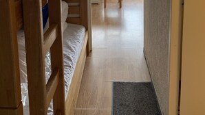 Una habitación con literas, un escritorio y vistas a edificios y montañas a través de una ventana.