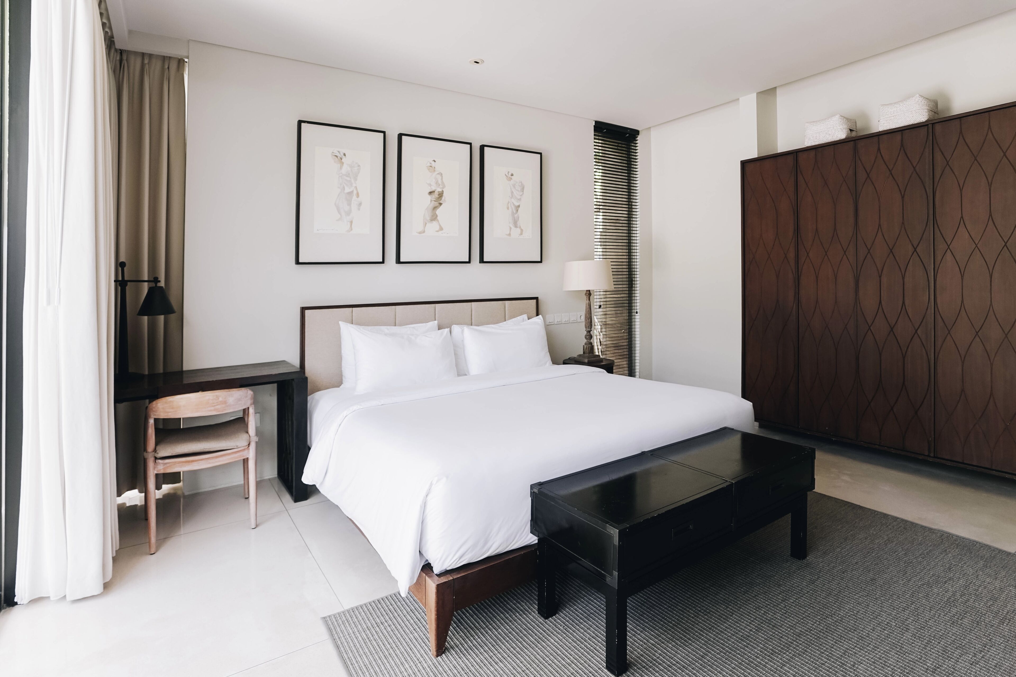 Une chambre d’hôtel avec un grand lit, un bureau, une chaise, une table basse et une armoire.