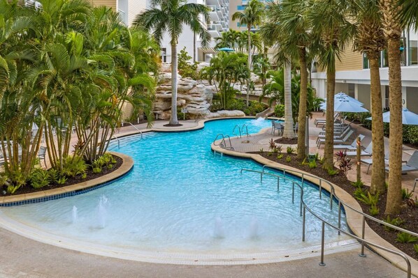 Relax by the resort pool surrounded by lush vegetation and lounge chairs.