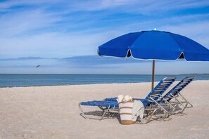Relax by the ocean with a comfortable beach umbrella and lounge chairs.