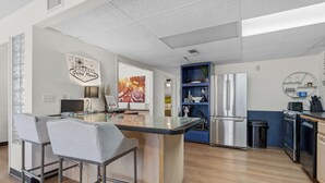 A modern kitchen with a central island, bar stools, stainless steel appliances, and a blue accent wall.