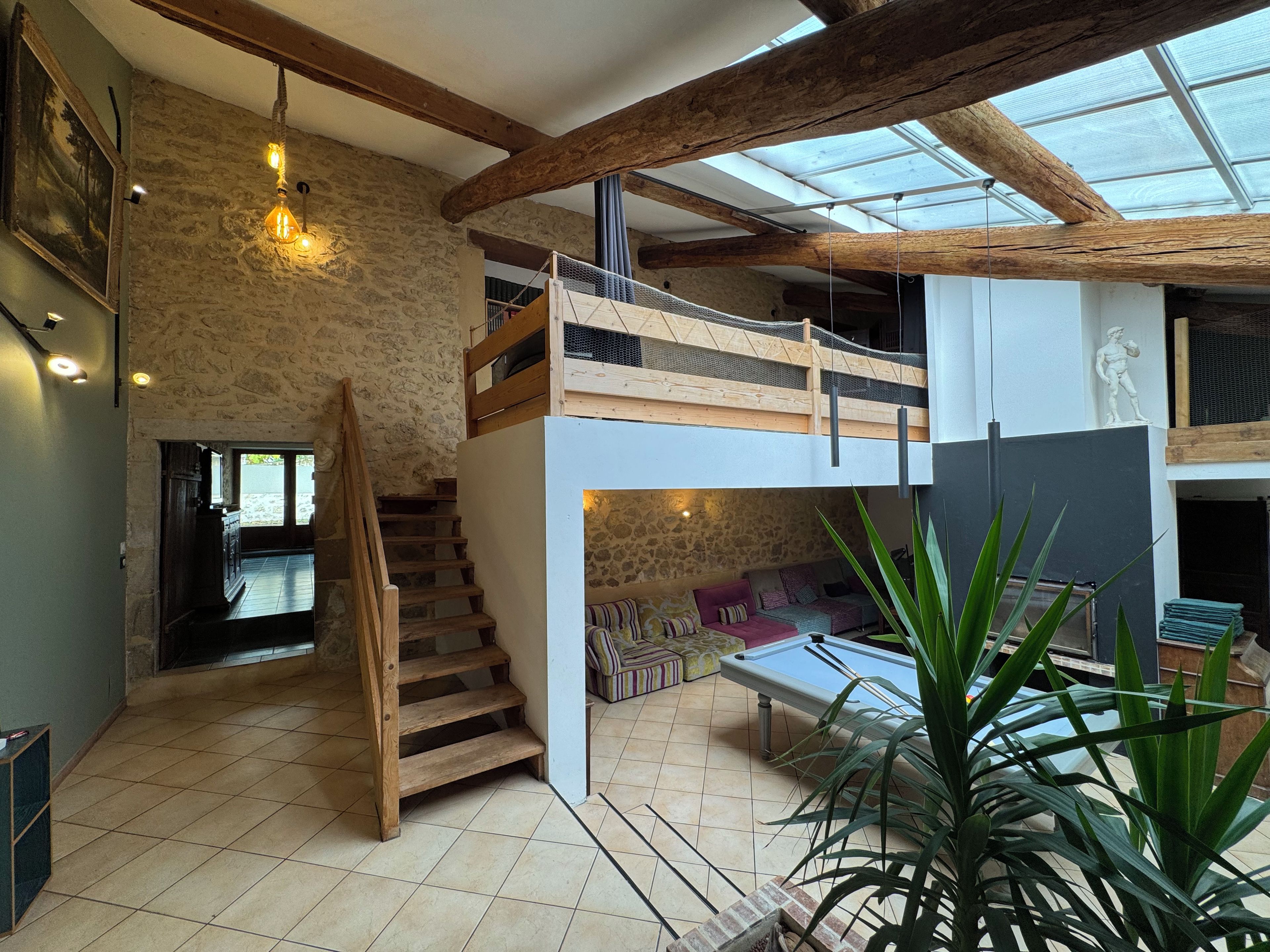 A spacious interior with a wooden staircase, a mezzanine level, and a large skylight.