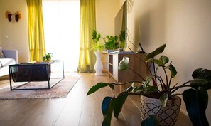 A living room with a sofa, coffee table, and potted plants. - Corner Cottage (Dandenong North)